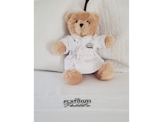 A teddy bear wearing a white robe on a bed
