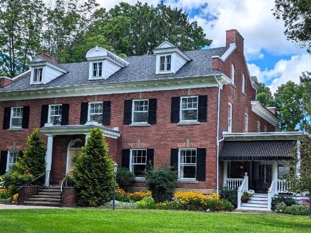 exterior image of a brcik inn with expansive green lawn