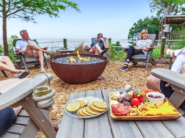 Guests enjoying charcuterie board around firepit at Jubilee Suites in Fairhope, AL