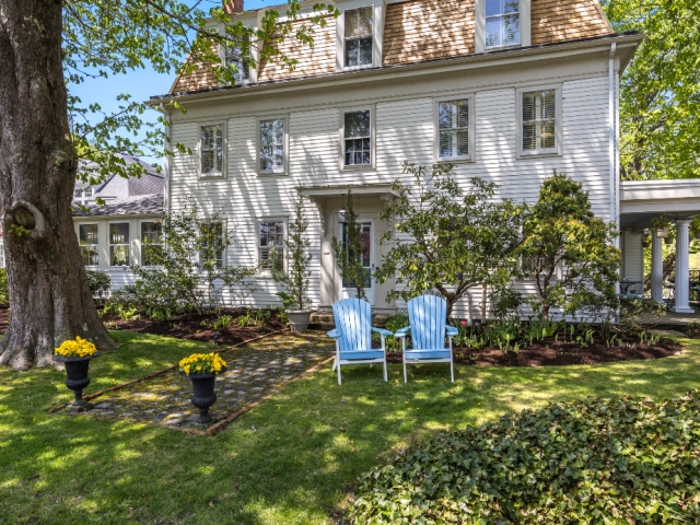Classic New England-style inn with white clapboard siding, Adirondack chairs on a manicured lawn, and a welcoming sign that reads “Old Manse Inn – Brewster, Cape Cod.”