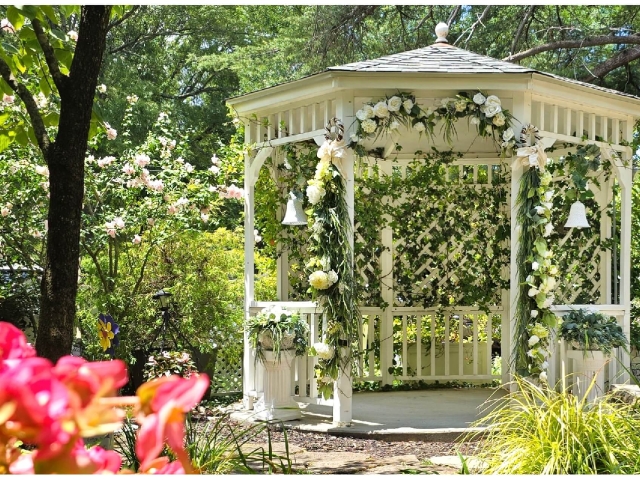 Gazebo decorated for wedding in blooming garden.