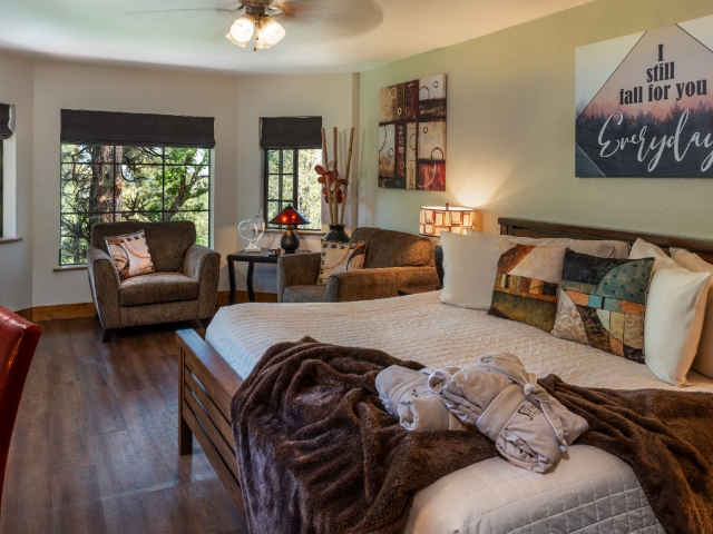 guest room with king bed in front of large windows with 2 oversized chairs in front of them