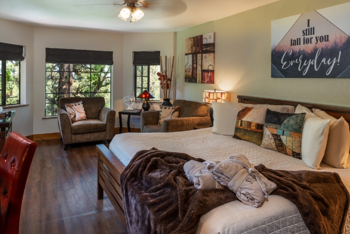 guest room with king bed in front of large windows with 2 oversized chairs in front of them