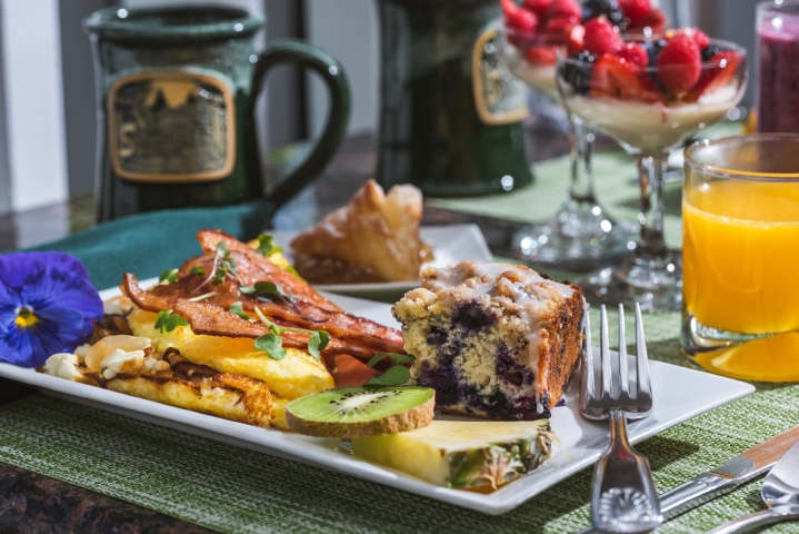 breakfast plate with omelet, bacon, blueberry cake and fresh fruit