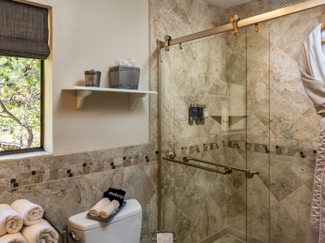 tiled shower with glass doors and rain shower