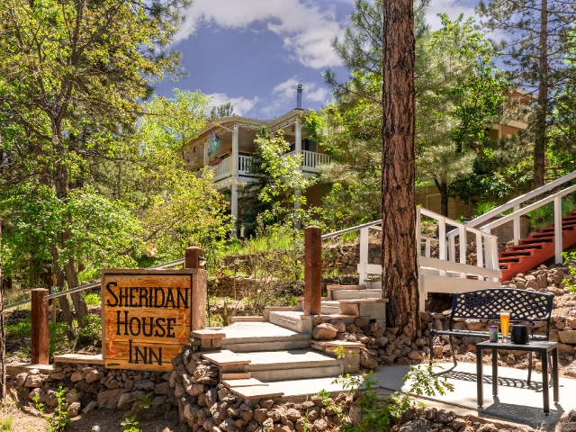 front of inn with pine trees, stairway, bench and Sheridan House Inn sign