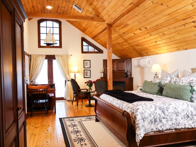 large suite with California king sleigh bed with cathedral ceiling, chairs and desk