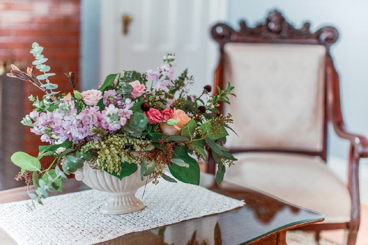 A vase of soft blooms resting on a lace‑draped table in the quiet parlor of Finger Lakes Bed and Breakfast at Hutton Farm.