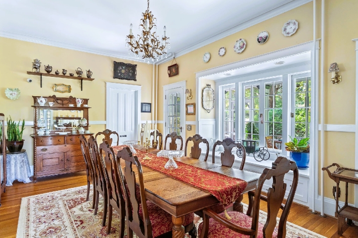 A historic dining room with a long wooden table, carved chairs, and soft daylight warming the timeless details.