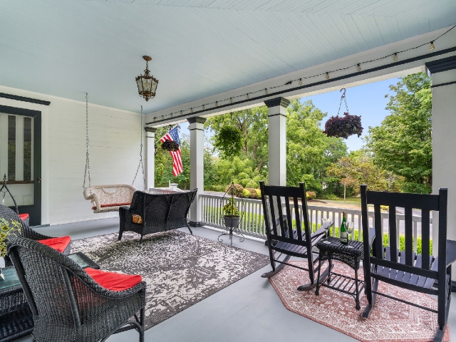 A welcoming porch with soft seating, hanging flowers, and gentle light drifting in from a quiet tree‑lined street.