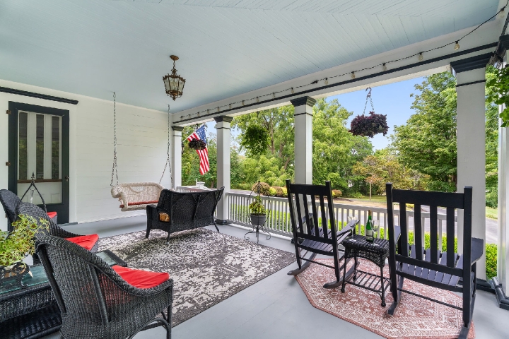 A welcoming porch with soft seating, hanging flowers, and gentle light drifting in from a quiet tree‑lined street.