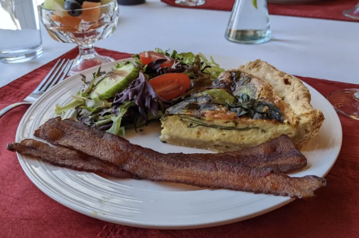 Gourmet breakfast at Castle in the Country featuring a savory quiche, bacon, and fresh salad