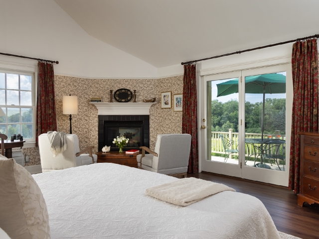 guest room with a king bed, seating area, fireplace, and private deck