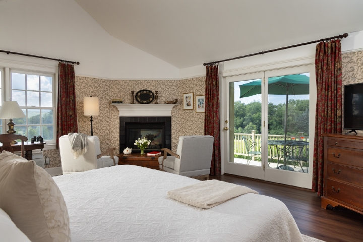 guest room with a king bed, seating area, fireplace, and private deck
