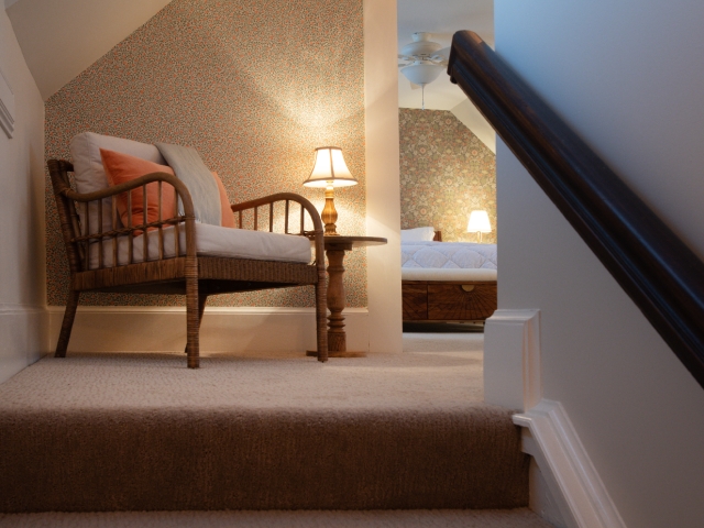 Cozy sitting area in the Honeymoon Suite, warmly illuminated by a lamp, with a glimpse of the bedroom and king-size bed beyond.