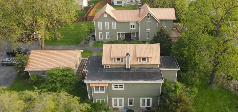 Prairie Guest House welcomes guests amid native trees and lush green meadows, viewed from above.