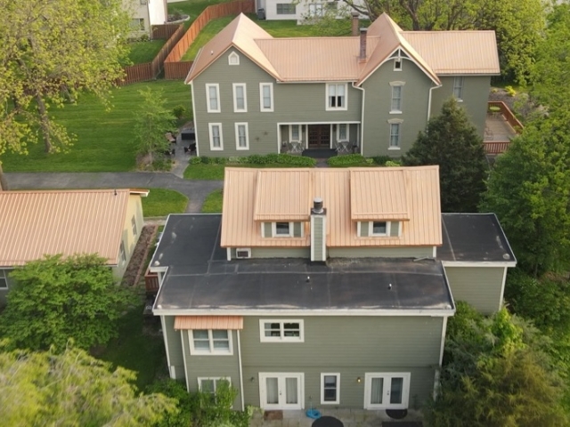 Prairie Guest House welcomes guests amid native trees and lush green meadows, viewed from above.