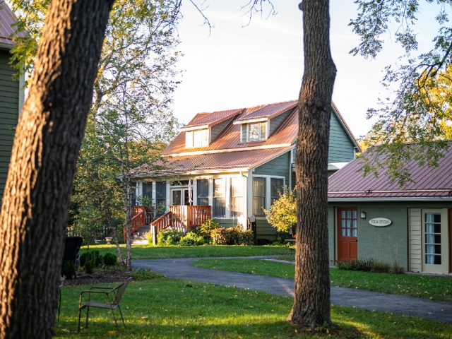 Sunlight bathes Prairie Guest House, nestled among beautifully manicured courtyard gardens and surrounded by towering native trees.