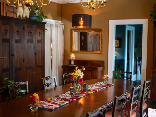 Elegant mahogany L. S. Ayres boardroom table and chairs fill the dining room, beautifully adorned with colorful zinnias grown in the Prairie Guest House gardens.