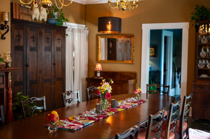 Elegant mahogany L. S. Ayres boardroom table and chairs fill the dining room, beautifully adorned with colorful zinnias grown in the Prairie Guest House gardens.
